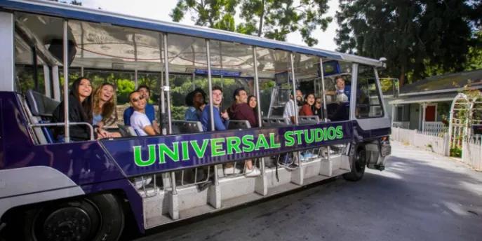 Guests smiling and waving from the Universal Studios electric tram during the studio tour