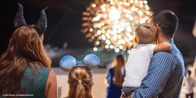 A family wearing Disney ears looking out at a nighttime fireworks display