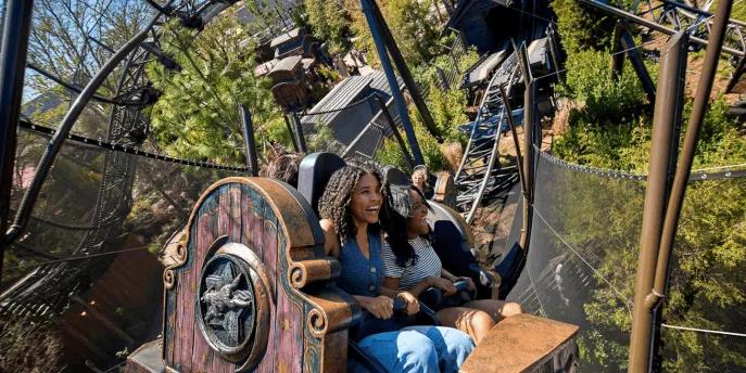 Two women smiling while riding the Curse of the Werewolf roller coaster