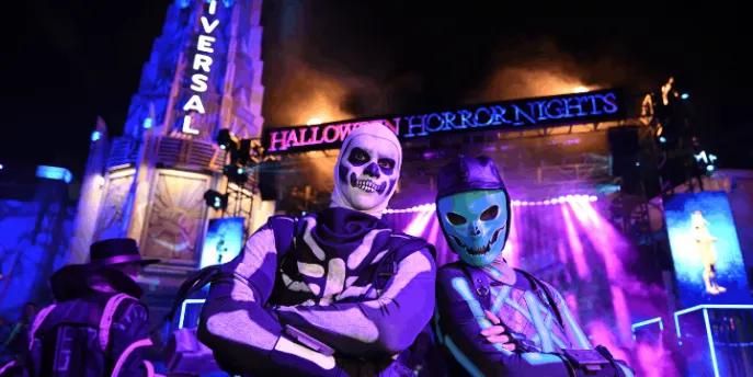 Two costumed Fortnite characters posing in front of an illuminated Halloween Horror Nights sign at Universal Studios