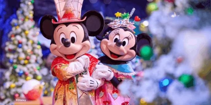 Mickey and Minnie Mouse wearing festive holiday outfits posing in front of snow-flocked Christmas trees