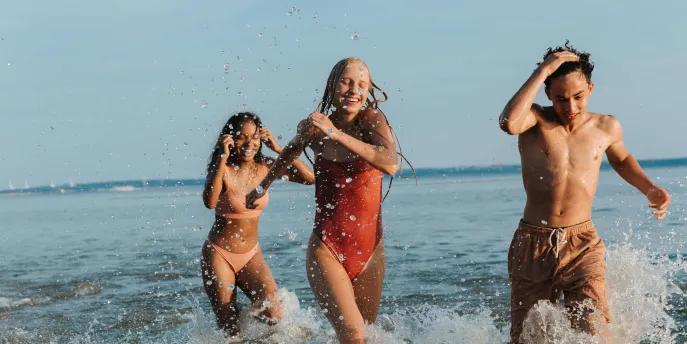 Three friends laughing and splashing in the sea on a summer holiday.