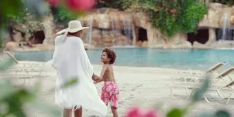 A woman and child walking on the beach at Serenity Bay 