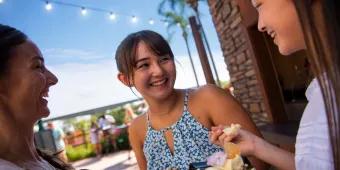 Three young women smiling while eating food at EPCOT