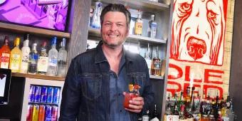 Blake Shelton holding a glass of sangria behind a bar