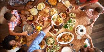 A family dining at a round wooden table covered in food