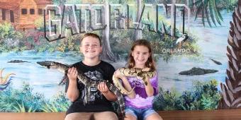Boy holding a baby alligator and girl holding a snake at Gatorland