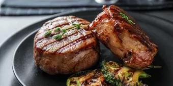 Two steak filets on a plate with grilled green vegetables