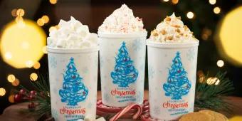 Three hot chocolates topped with cream in cups with Christmas trees and the writing "SeaWorld's Christmas Celebration" written on them