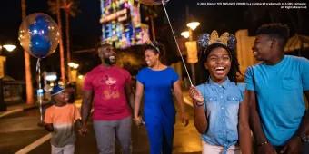 After Hours at Disney's Hollywood Studios A family with two adults and three children holding balloons and walking in front of Tower of Terror at night