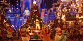 Mickey Mouse standing in front of a Christmas Tree on a parade float. Characters such as Peter Pan, Donald Duck and Pluto dance in front of it