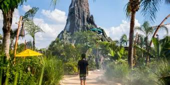 A child in a wetsuit walking along a path lined with plants towards the volcano at Volcano Bay