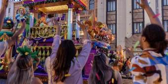 Mardi Gras Parade Guests watching a large Mardi Gras themed parade float while confetti is falling around them