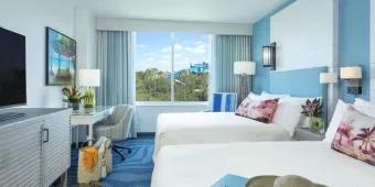 A Room at Loews Sapphire Falls Hotel Two double beds facing a desk, chest of drawers and TV, next to window looking out on Islands of Adventure