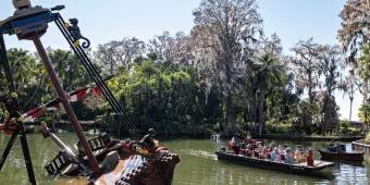 A boat on a waterway sailing past a half sunken LEGO pirate ship