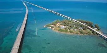 Two parallel bridges over clear blue seas and a small sandy island