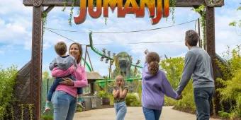 A family standing in front of a sign reading World of Jumanji. One child is holding her face as if in shock