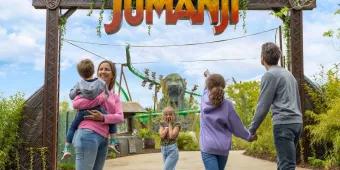 World of Jumanji A family standing in front of a sign reading World of Jumanji. One child is holding her face as if in shock