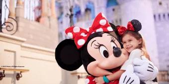 A young girl hugging Minnie Mouse in front of Cinderella Castle at Walt Disney World