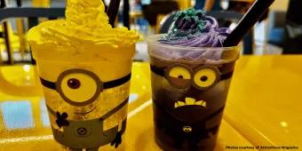 Two cups with faces designed to look like Minions, one filled with a yellow drink and one filled with a purple drink