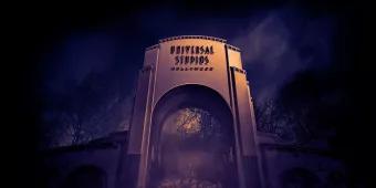A large archway reading Universal Studios Hollywood surrounded by fog at night