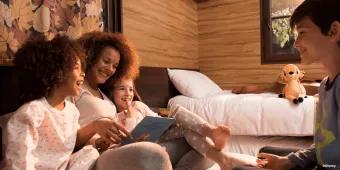 A family sat on a double bed in a cabin reading a book