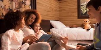 Disney Davy Crockett Ranch A family sat on a double bed in a cabin reading a book