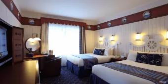 A nautical themed hotel room with two double beds and a dresser