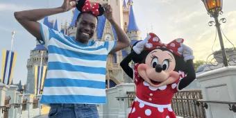 A man wearing Minnie ears standing with Minnie Mouse in front of Cinderella Castle