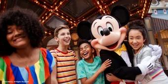 Mickey Mouse hugging and posing with 4 young adults