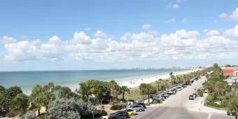 A view down a road running along a white sandy beach and blue ocean