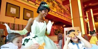 Tiana smiling with children sat at a table eating breakfast in Disneyland