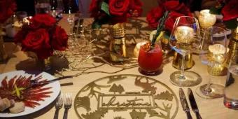 A table decorated for Christmas with red flowers and gold place settings