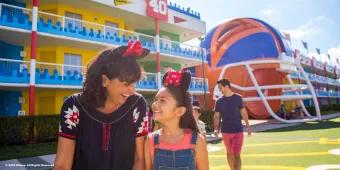 Disney's All-Star Sports Resort A woman and girl walking in front of a hotel designed to look like an American football pitch