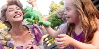 Rapunzel and guest smiling and playing with plush toy of Pascal in front of Rapunzel's tower
