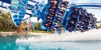 Ride shaped like manta ray in motion, curving round bend on top of lake with water being sprayed up towards the riders