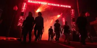 Halloween Horror Nights at Universal Orlando Looking up at people walking underneath an archway with a glowing Halloween Horror Nights sign