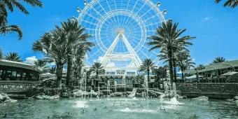 Large white ferris wheel with fountains in front and palm trees. Beneath the wheel is a sign which says SEA LIFE.