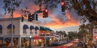 A street of shops and restaurants with the sun setting in the distance