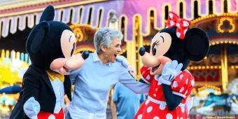 Orlando for Seniors An older woman smiling with Mickey and Minnie