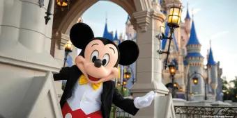 Magic Kingdom Park Mickey Mouse standing in front of Cinderella Castle with his arm outstretched