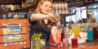Flavours of Florida at Disney Springs A woman pouring colourful drinks behind a wooden bar