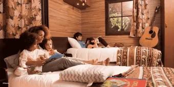 Disney Davy Crockett Ranch at Disneyland Paris A family relaxing and reading on beds in a wooden cabin at Davy Crockett Ranch