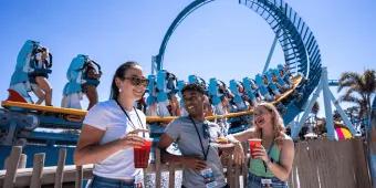 Seven Seas Food Festival at SeaWorld Orlando Three young adults stood in front of the Pipeline rollercoaster drinking cocktails and eating festival plates