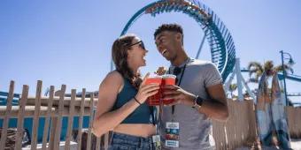SeaWorld Seven Seas Food Festival A couple posing with drinks in front of the Pipeline rollercoaster at SeaWorld