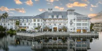 A beautiful white large hotel on the edge of a large lake, reflecting in the water and the gorgeous clear sky above. 