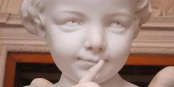 Cupid supporting revenge on an ex Statue of cupid (young boy) holding finger to lips as if to say shhhh with a mischevious expression