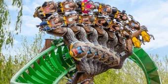 Monkey shaped rollercoaster cart twisting around a turn on the green rollercoaster track.