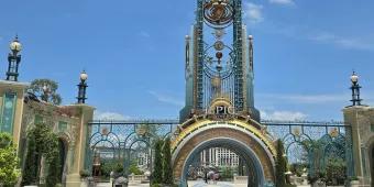 Universal Epic Universe Grand entrance with a semicircle portal opening and above there's a statue of a planet and star constellation.