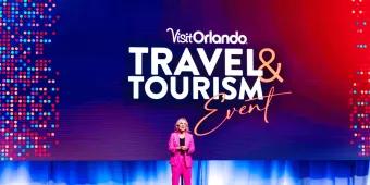 Visit Orlando Travel & Tourism Conference Visit Orlando Travel & Tourism Conference - woman speaking and announcing in a pink suit.